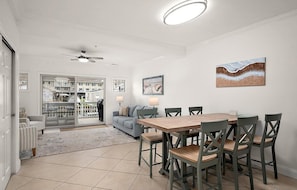 Un coin repas avec une table et des chaises en bois, un ventilateur de plafond et des œuvres d’art accrochées aux murs.