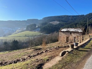 Ein Steinhaus mit rustikalem Aussehen, gelegen an einem Hang mit Blick auf ein Tal und einen Fluss.