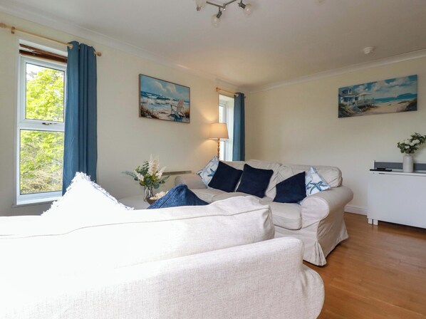 A room with a bed, a sofa, a desk, and two paintings on the wall.