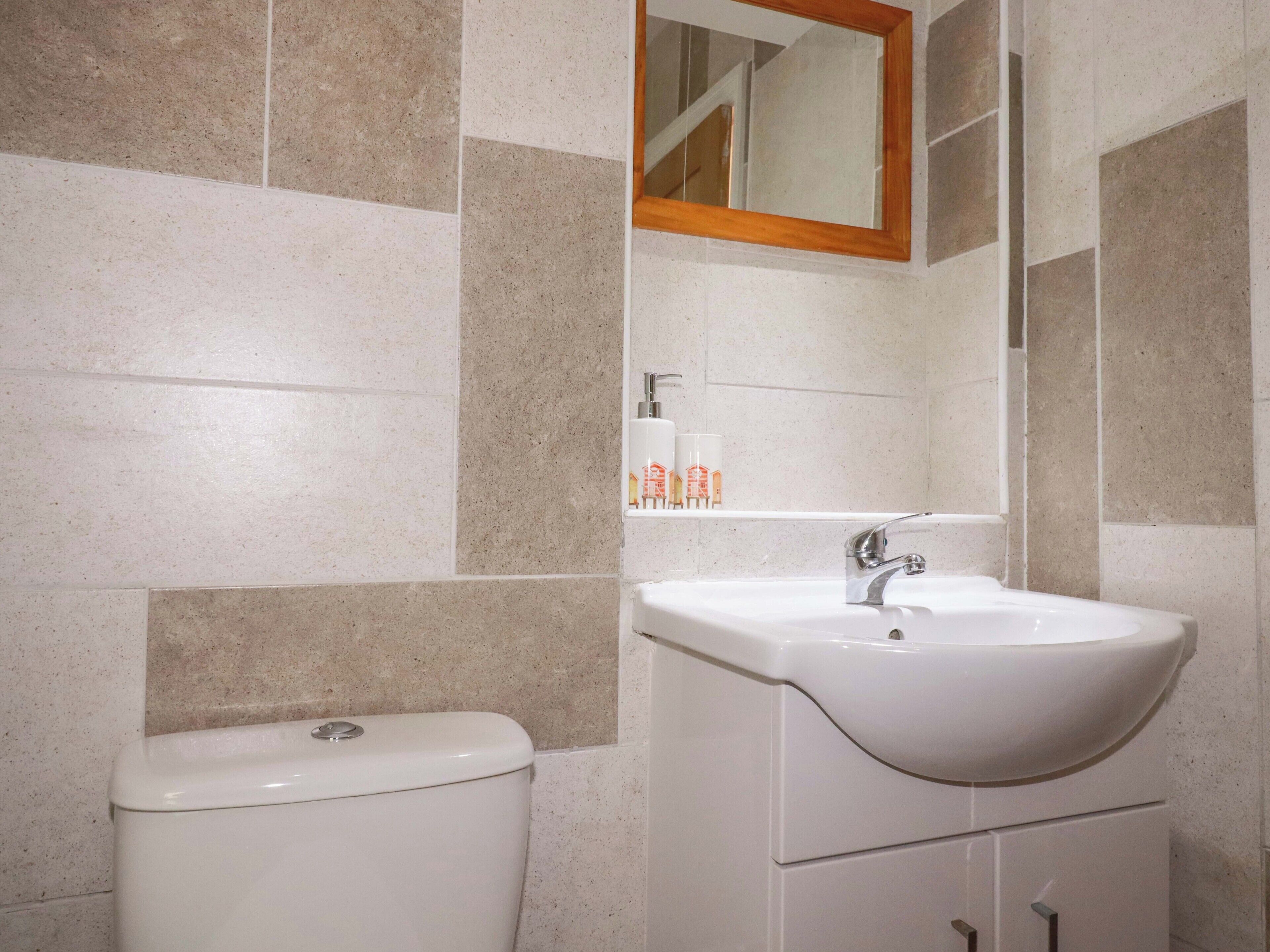 A bathroom with a toilet, sink, mirror, and toiletries on the wall.