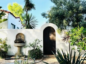 Ein Garten mit Brunnen, einer Tür und einer Wand mit Stuckverzierungen.