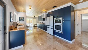 A modern kitchen with dark cabinetry, a wooden ceiling, and a marble floor. - Aloha House: Beautiful North End pool home (Anna Maria)