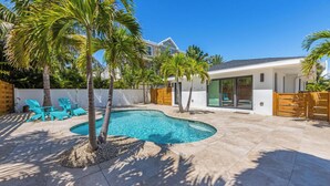 A modern house with a swimming pool, palm trees, and outdoor seating. - Aloha House: Beautiful North End pool home (Anna Maria)