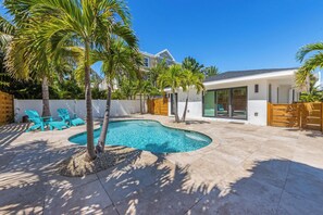 A modern house with a swimming pool, palm trees, and outdoor seating. - Aloha House: beautiful north end pool home (Anna Maria)