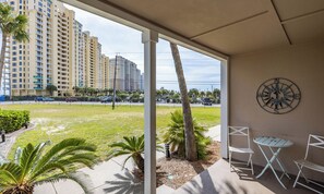 A covered outdoor area with a view of high-rise buildings, a compass wall decoration, and outdoor furniture. - Sea Sparrow Nest by PKRM (Pensacola)