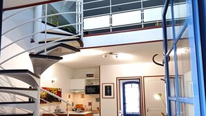 Ein kompaktes Apartment mit Wendeltreppe, einer Küche, einer Essecke und einem Schachbrettfußboden.
