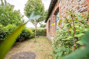 A stone building with a brick facade, surrounded by lush greenery and a well-maintained lawn. - 40 minutes from Le PUY DU FOU Gîte with swimming pool and private garden (Montaigu-Vendée)