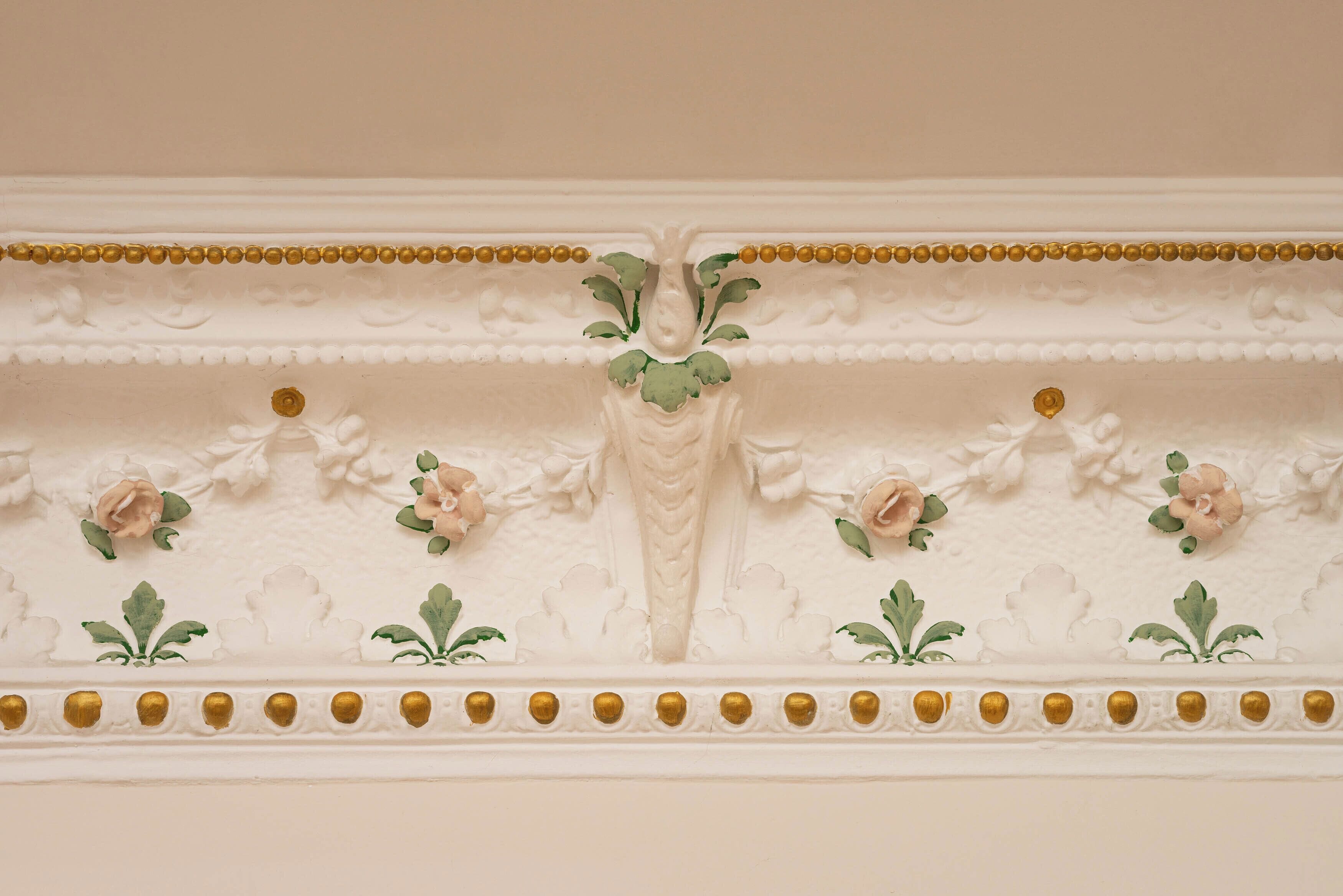 A detailed architectural ceiling with floral motifs and gold accents.