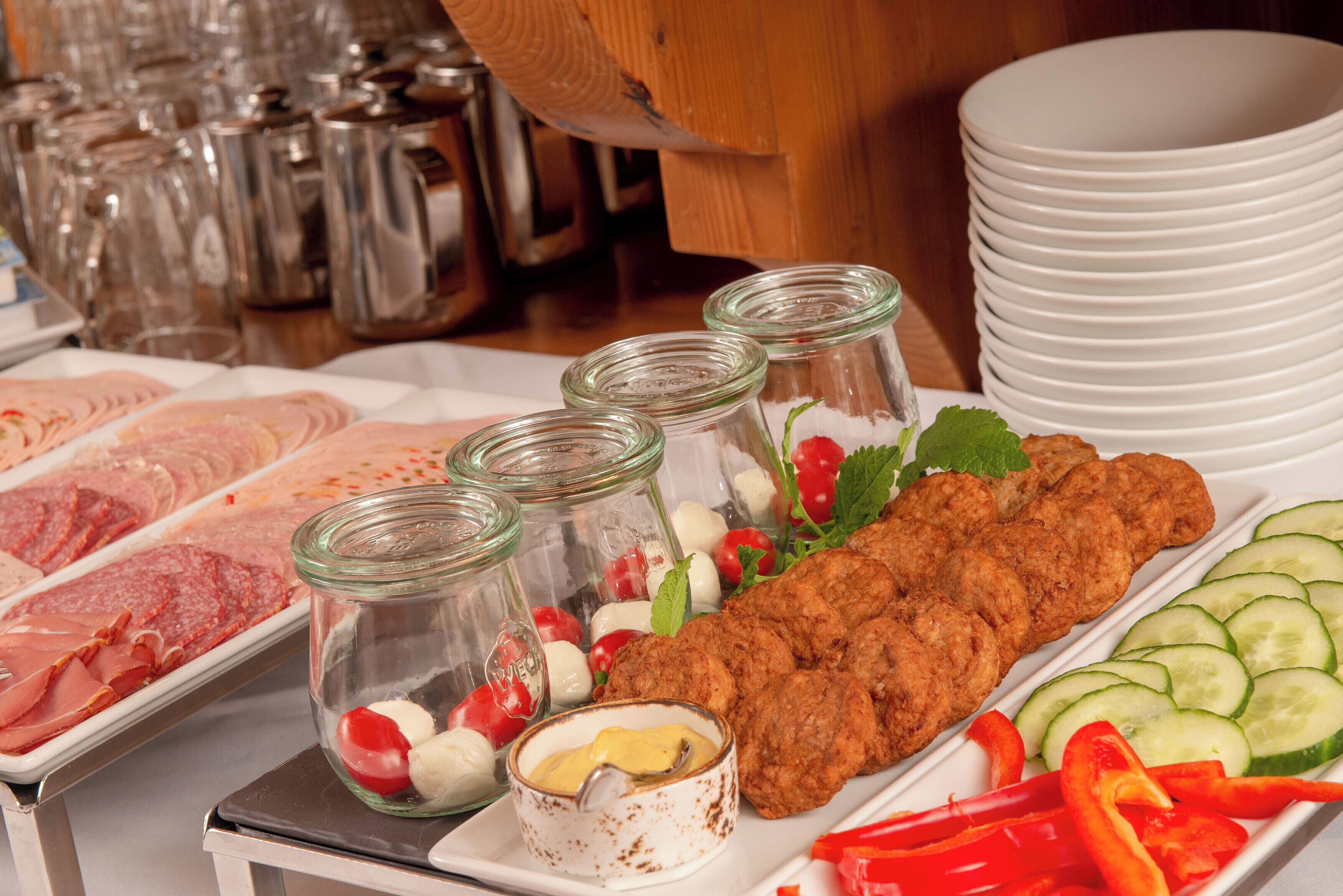 A buffet with various food items, including sliced meats, vegetables, and a long platter of fried items.