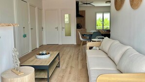 A modern living room with a sofa, a coffee table, and a dining area with chairs and a table. - La Cabine de Jeanne - 3 rooms close to beach, port, restaurants on foot (Saint-Gilles-Croix-de-Vie)