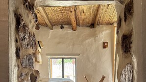Ein Zimmer mit einem Bett, Holzboden, einem Fenster und einer Steinwand.