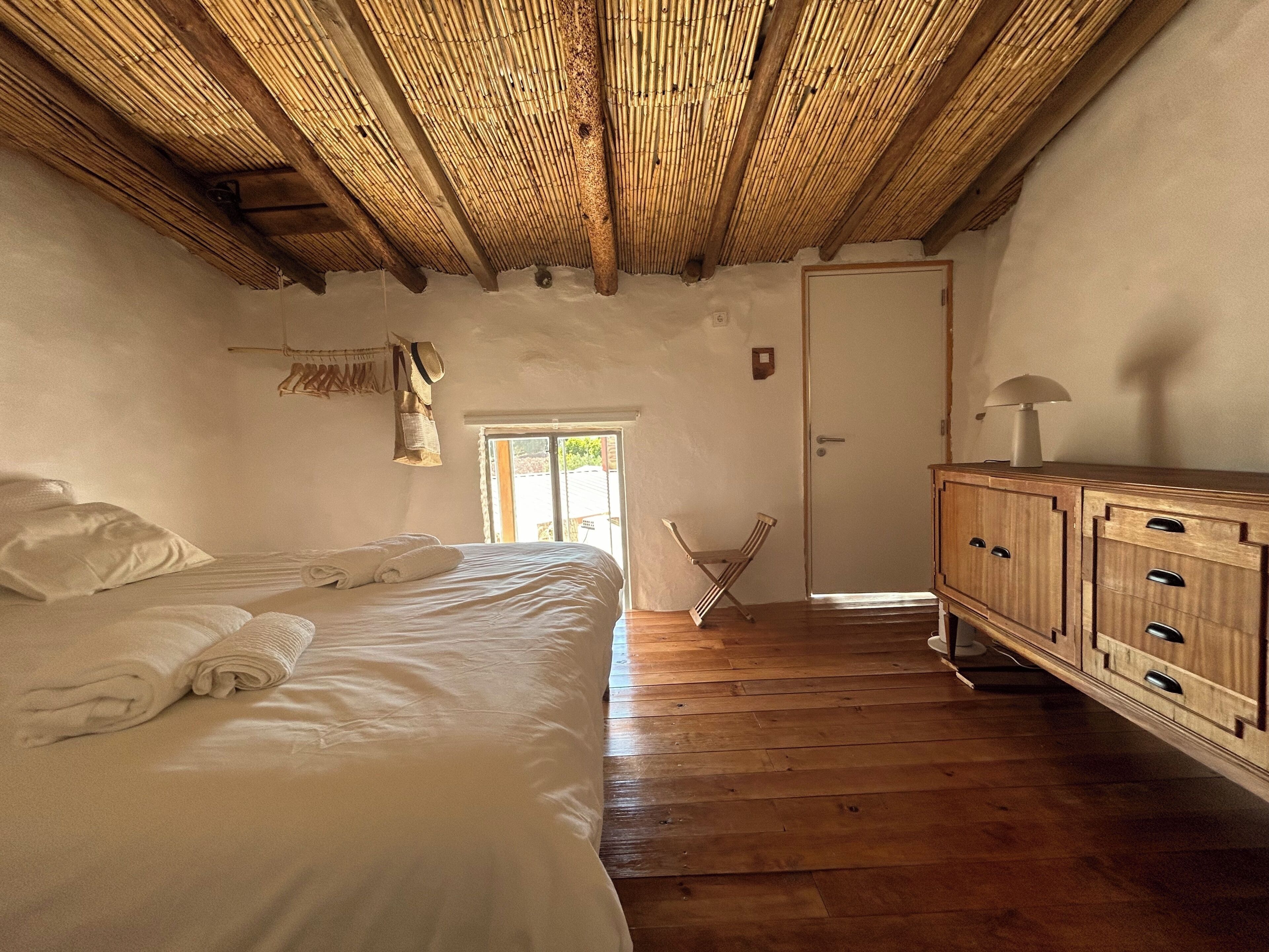 Un dormitorio con cama, armario de madera y puerta que da al exterior.