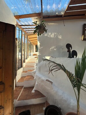A room with a wooden staircase, white walls, and a hanging plant. - Casa de Santa Catarina - Unique Authentic Charm (Faro)