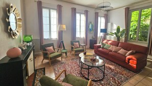 A living room with a sofa, chairs, a coffee table, and a view of greenery outside. - Libourne near Saint-Émilion, Villa Beauséjour (Libourne)