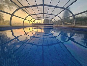 An indoor swimming pool with a curved roof and clear glass walls.