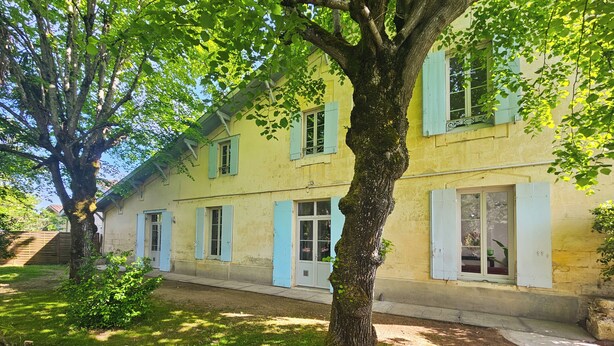 A two-story building with a garden, a tree in the foreground, and a clear sky. - Libourne near Saint-Émilion, Villa Beauséjour (Libourne)