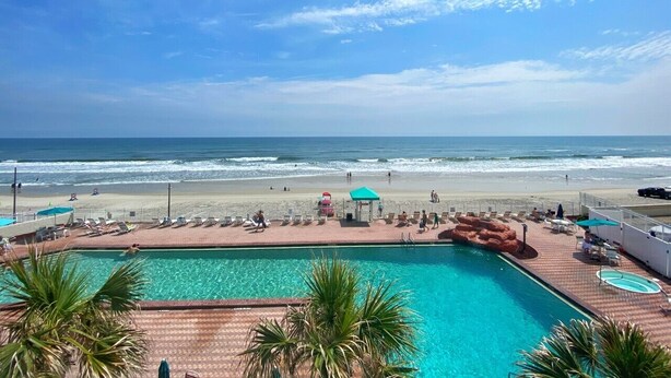 Zona de piscina con vista a la playa y al océano.