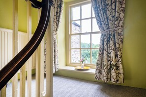 A room with a window, a wooden staircase, and a small table with a vase. - Palace Garden Cottage (Bishop Auckland)