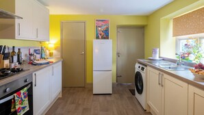 Una cocina con estufa, horno, refrigerador, lavadora y una ventana con flores.
