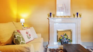 A living room with a sofa, a fireplace, a lamp, and a framed picture above the mantel.