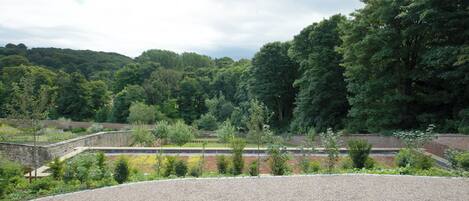 A gravel area with a stone wall and trees in the background.