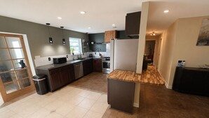 Una cucina moderna con mobili scuri, un'isola in legno e vista sull'area soggiorno.