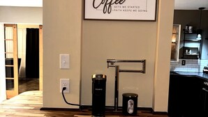 Un piano di lavoro in cucina con una macchina da caffè, un bollitore e un cartello a tema caffè.