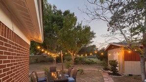 Un patio con tavolo e sedie, circondato da un muro in mattoni e alberi.