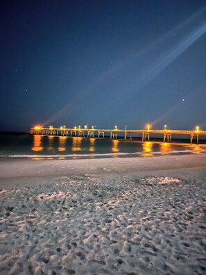 Eine Pier, die sich in das Wasser erstreckt, beleuchtet in der Nacht.