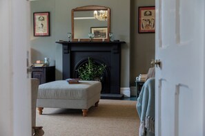A room with a fireplace, a mirror above it, and a door leading to another room. - The Clarence (Bishop Auckland)