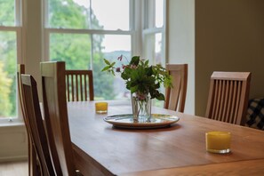 A wooden dining table with chairs, a vase with flowers, and two candles. - The Clarence (Bishop Auckland)