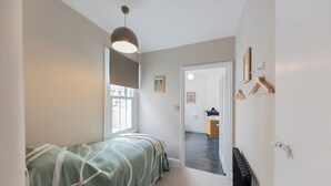 Ein Schlafzimmer mit Bett, Heizkörper und einer Tür zu einem anderen Raum.