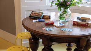 Ein runder Holztisch mit Blumen, Gesellschaftsspielen und Büchern.