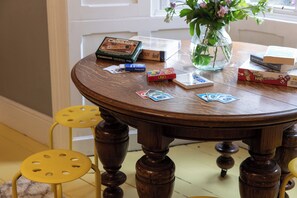 Ein runder Holztisch mit Blumen, Gesellschaftsspielen und Büchern.
