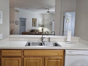A kitchen with a double sink, wooden cabinets, a ceiling fan, and a dishwasher. - Magical landings Villa by Paradise Resort Vacations BRAND NEW TO THE RENTAL MARKET (Kissimmee)