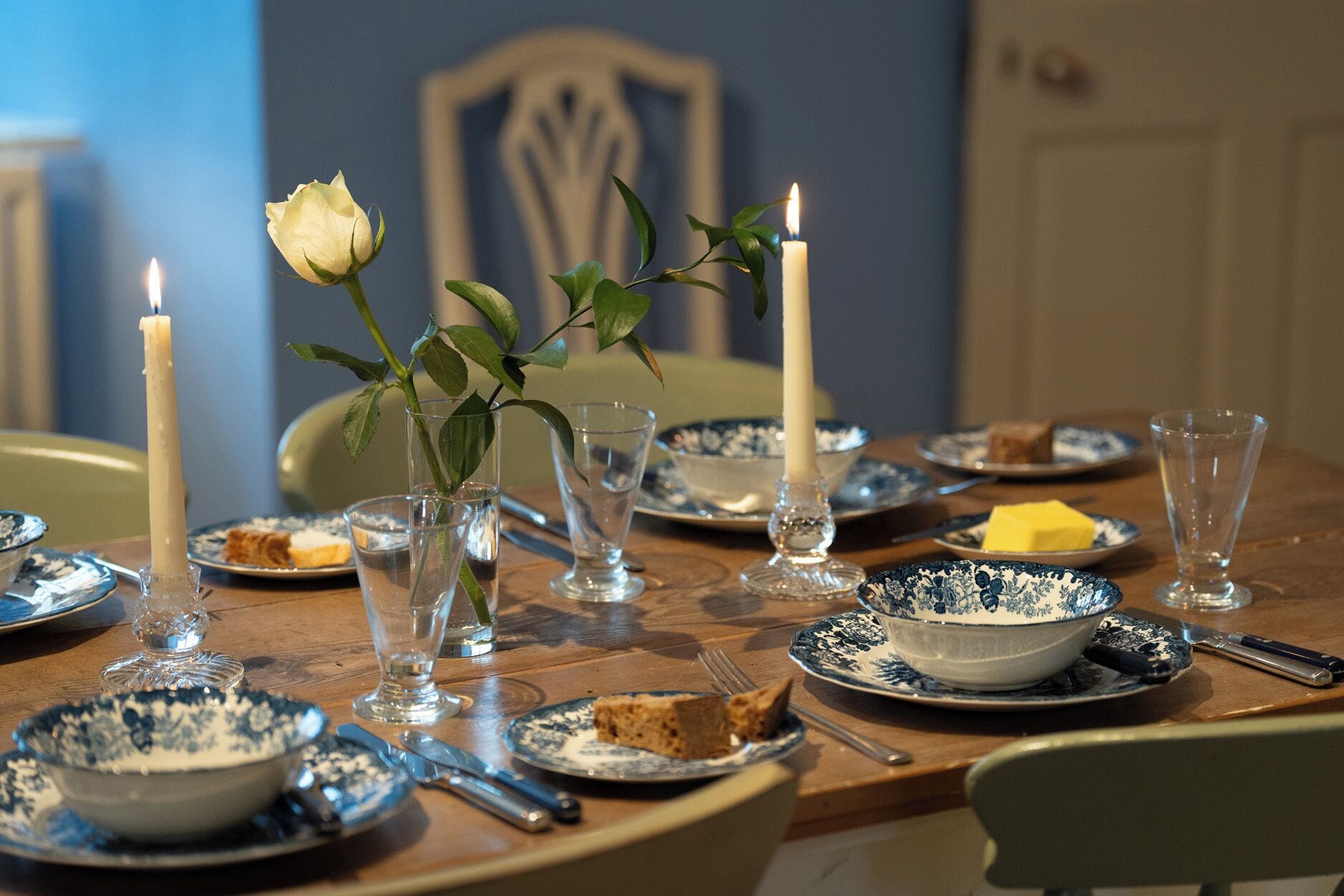 Une table à manger avec des assiettes, des verres et des bougies.