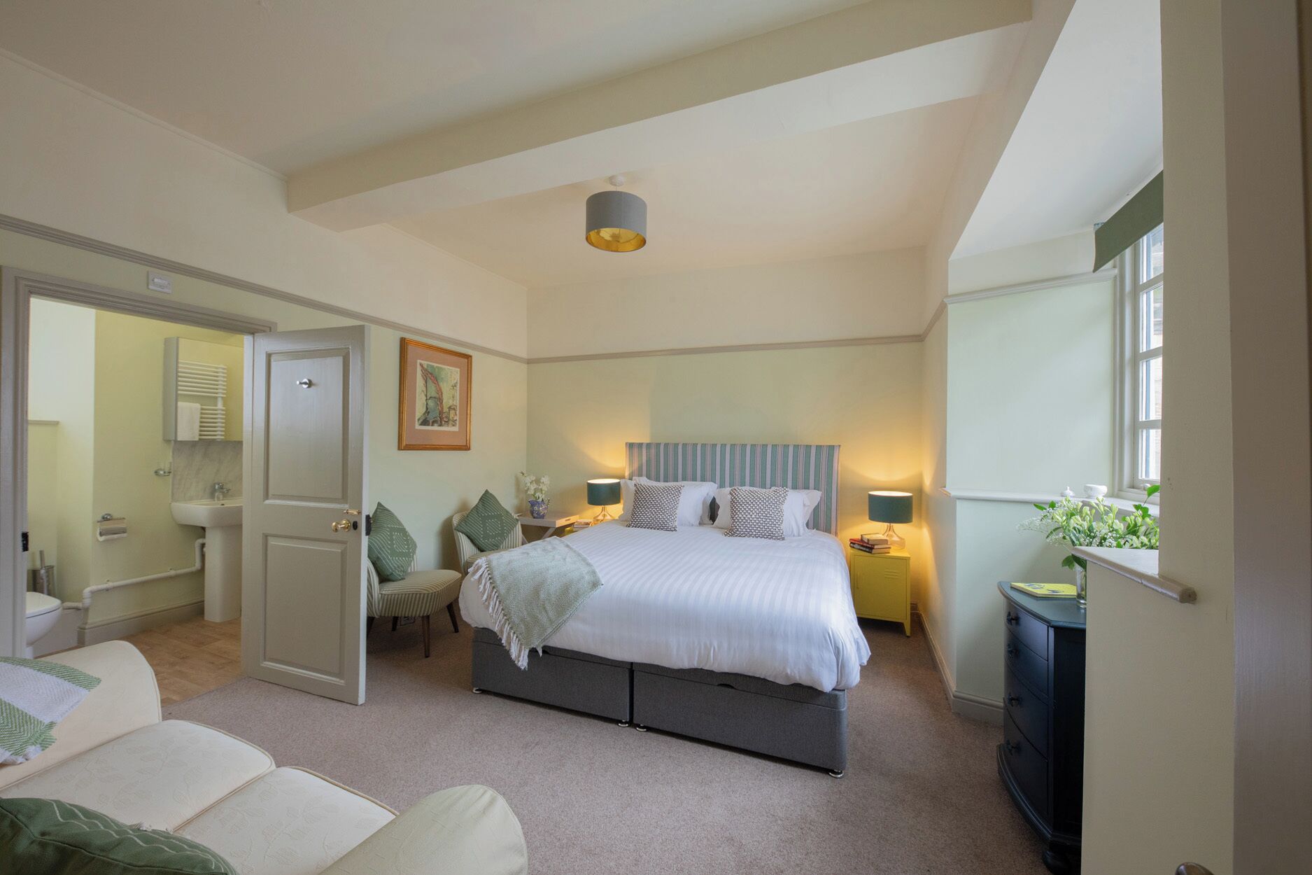 A bedroom with a bed, bedside tables, a window, and a door leading to a bathroom.