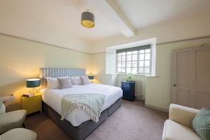 A bedroom with a bed, bedside tables, a window, and a door. - Churchill Cottage (Bishop Auckland)