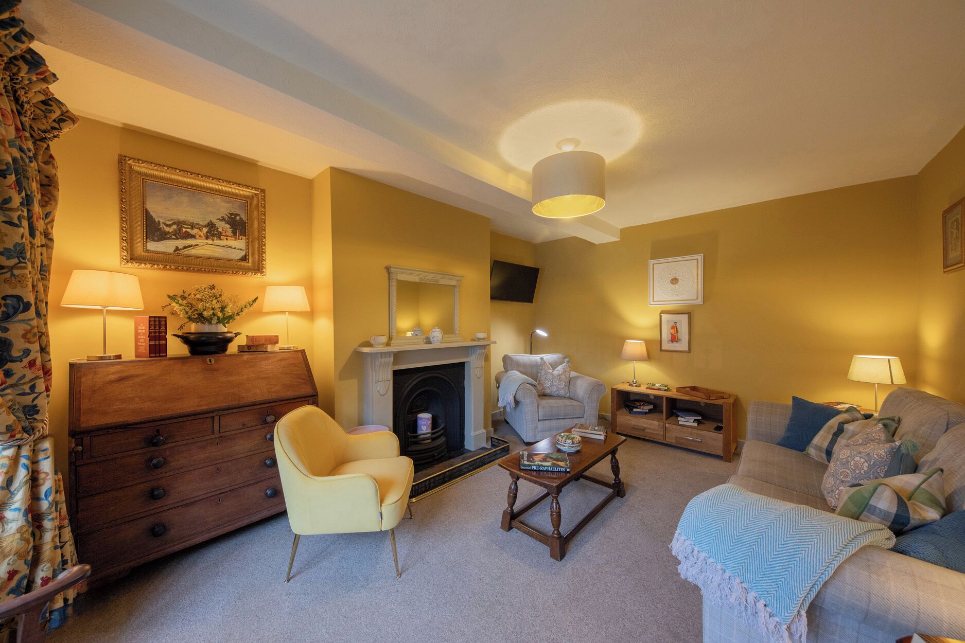A living room with a fireplace, a sofa, a chair, a coffee table, and a TV mounted on the wall.