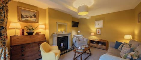 A living room with a fireplace, a sofa, a chair, a coffee table, and a TV mounted on the wall.