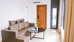 A modern living room with a sofa, a coffee table, a floor lamp, and a door with a number sign. - Wake Up to Sunshine in Ninh Binh's Old Quarter - Cozy 2BR for Families! (Hoa Lư)