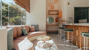 A modern interior with a curved sofa, a round table, bar stools, and pendant lighting. - Unique Deluxe King with a beautiful rooftop and pool (Playa del Carmen)