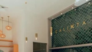 A modern hotel reception area with a wooden reception desk, bar stools, pendant lighting, and a green-tiled wall with the hotel name. - Unique Deluxe King with a beautiful rooftop and pool (Playa del Carmen)