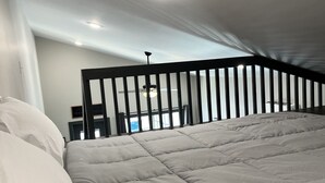 Ein Schlafzimmer mit einem Bett, einer Deckenleuchte und Blick auf einen Balkon.