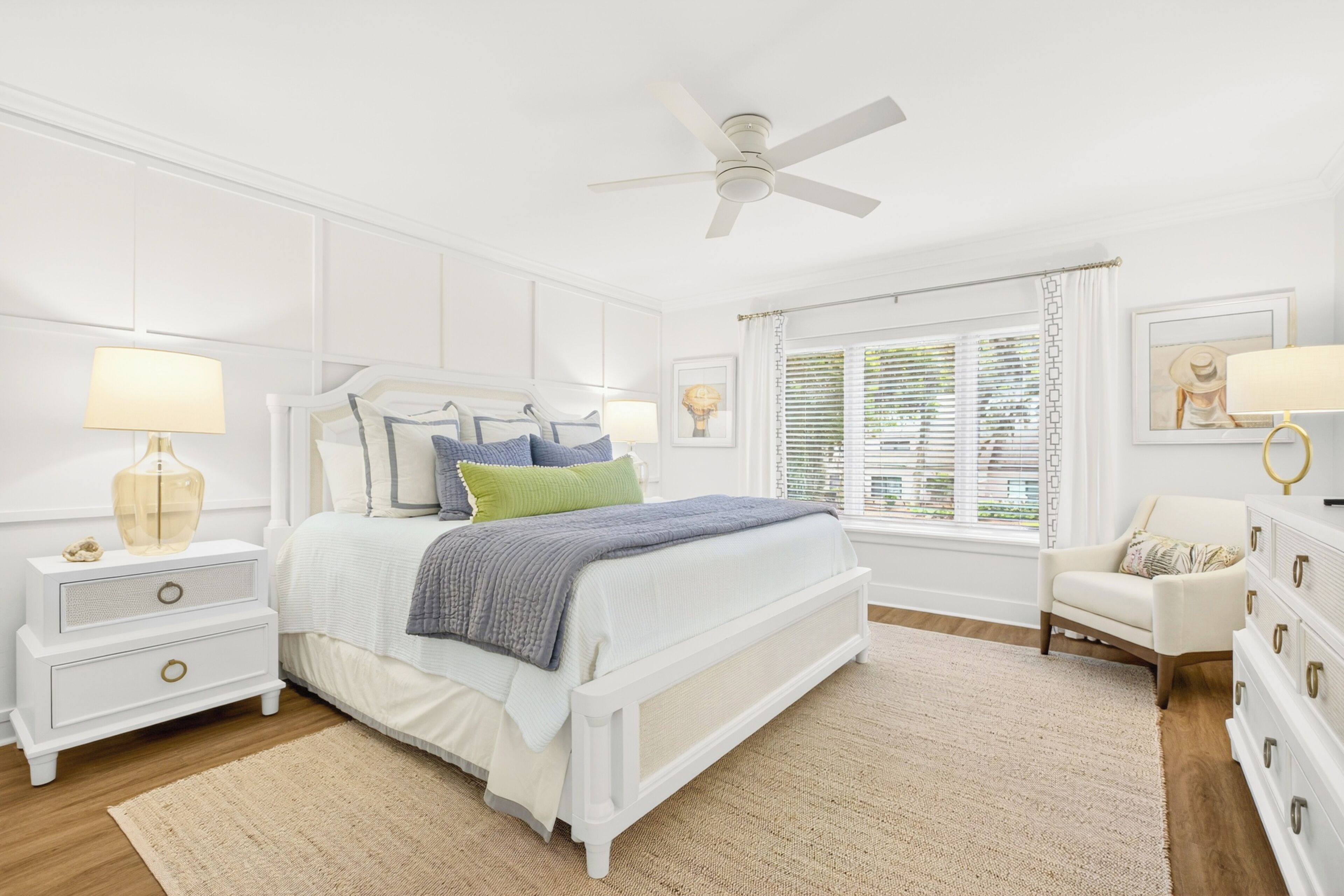 A bedroom with a bed, nightstands, a dresser, a ceiling fan, and a window with blinds.