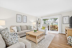 Ein Wohnzimmer mit Sofa, Couchtisch, Sessel und einem TV-Schrank.