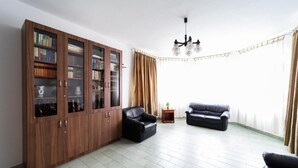 A living room with a large wooden cabinet, two black leather sofas, a small side table, and a chandelier. - VILLA LOTUS PANZIÓ (Zalakaros)