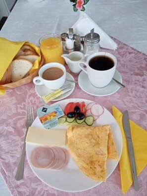 Desayuno con pan, huevos, queso y una taza de café sobre una mesa.