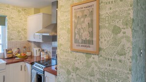 A kitchen with white cabinets, a stove, and a framed picture of flowers on the wall. - Sheriff's Tower Cottage - West (Bishop Auckland)