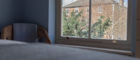 Una habitación con ventana, cama y silla.